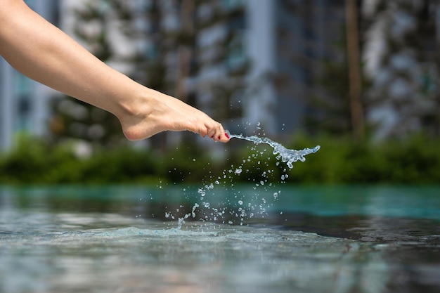 Closeup da perna de uma menina desce na piscina O pé toca a água Verifica a temperatura da água antes de nadar