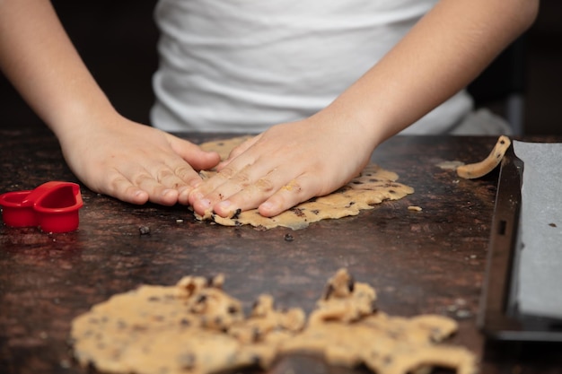 Closeup das mãos da criança preparando biscoitos