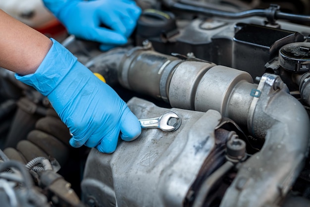 Closeup das mãos de um mecânico de automóveis que verifica o óleo no motor do carro técnico de manutenção e inspeção de motores de veículos