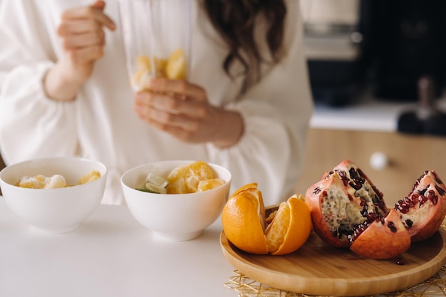 Closeup das mãos de uma garota que faz um coquetel de desintoxicação de frutas na cozinha dieta para perda de peso