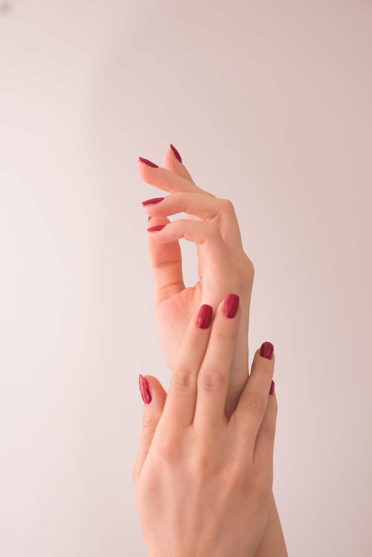 Foto closeup das mãos de uma jovem com longa manicure vermelha nas unhas contra fundo branco