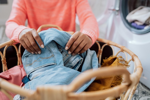 Closeup das mãos de uma mulher sentada no chão da lavanderia classificando roupas