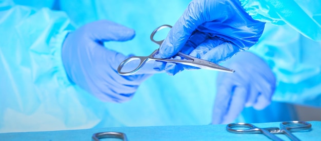 Closeup das mãos dos cirurgiões no trabalho na sala de cirurgia em tons de azul