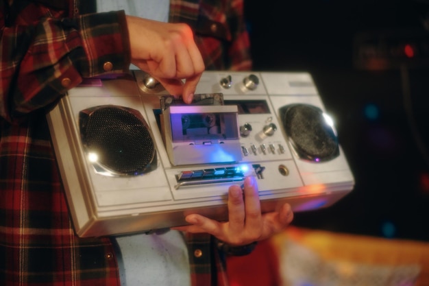 Closeup de adolescente colocando fita cassete para ligar a música no gravador
