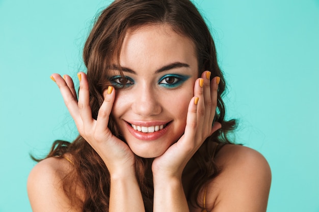 Closeup de adorável mulher encantadora com maquiagem linda, sorrindo e segurando as bochechas