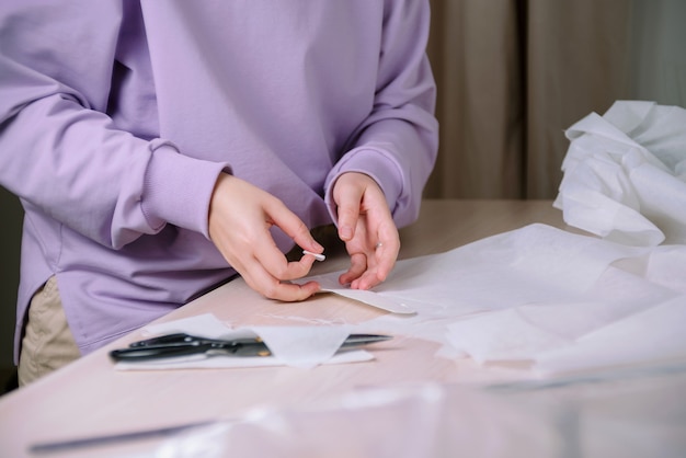 Closeup de alfaiate trabalhando com padrões de costura de papel em sua oficina