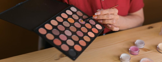 Closeup de banner de mulher segurando pincel de maquiagem e blush e paleta de sombras conceito de beleza e cosméticos