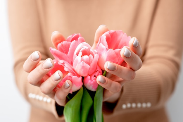 Closeup de botões de tulipa rosa nas mãos de uma jovem. flores cor de rosa em mãos femininas