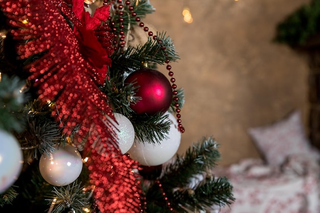 Closeup de bugiganga vermelha e branca pendurada em um fundo abstrato de galho de natal decorado com luzes desfocadas sala decorada para o ano novo e natal