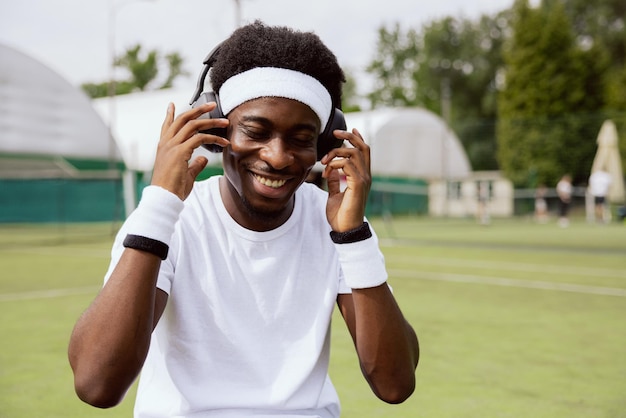 Closeup de cara de aparência africana usando fones de ouvido na cabeça, ele está vestindo camiseta branca