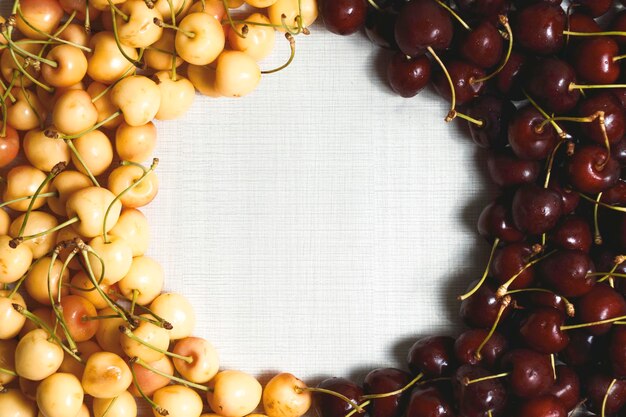 Closeup de cerejas maduras frescas e saborosas cerejas amarelas e vermelhas em uma mesa branca Copiar espaço