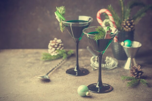 Closeup de coquetéis verdes em taças de martini com folhas de hortelã sobre cinza