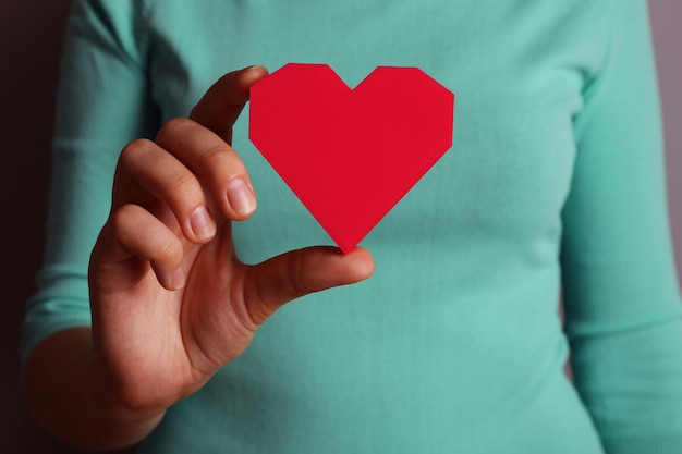 Closeup de coração de quebra-cabeça de plástico na mão feminina