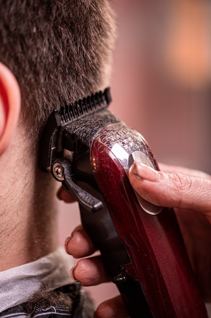 Closeup de corte de cabelo. mãos segurando uma máquina de cortar cabelo.