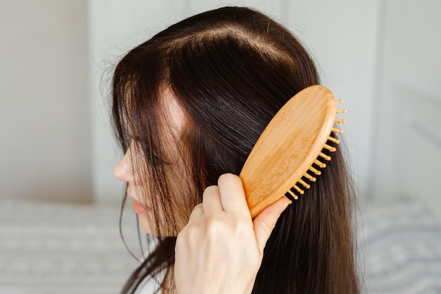 Closeup de cuidados com os cabelos de mulher escovando o cabelo com escova Retrato de mulher escovando o cabelo longo e saudável com escova de cabelo