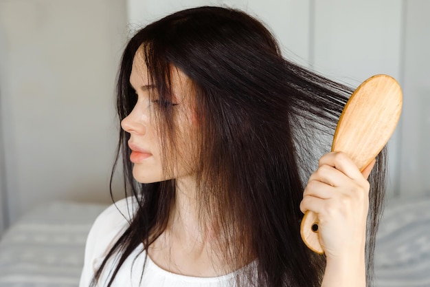 Closeup de cuidados com os cabelos de mulher escovando o cabelo com escova Retrato de mulher escovando o cabelo longo e saudável com escova de cabelo