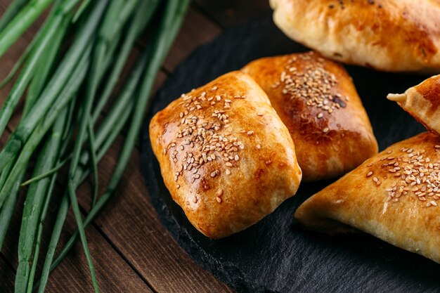 Closeup de diferente torta oriental assada com carne samsa na placa de pedra preta