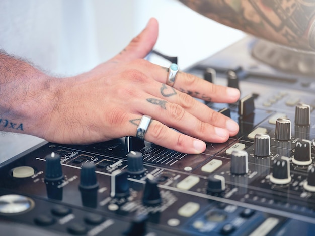 Closeup de DJ tatuado masculino irreconhecível usando equipamento eletrônico enquanto toca música