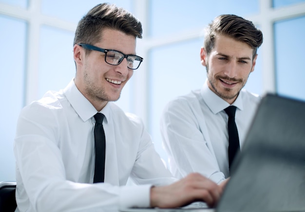 Closeup de empresário sorridente feliz ou empregador trabalhando em laptop digital no interior do escritório moderno