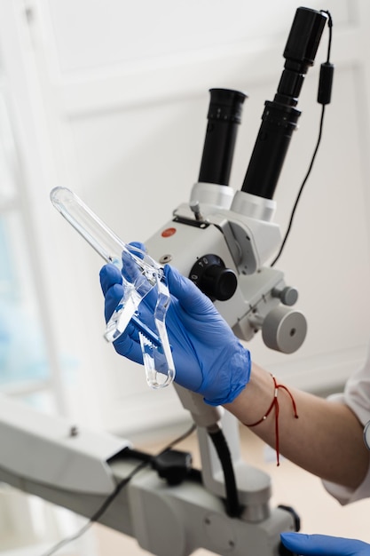 Foto closeup de espéculo nas mãos do ginecologista para procedimento de colposcopia para examinar de perto a vagina do colo do útero e a vulva da menina na clínica de ginecologia