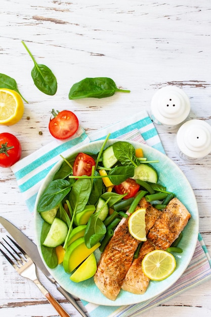 Closeup de filé de salmão grelhado com tomate espinafre pepino e salada de abacate Vista superior Espaço de cópia