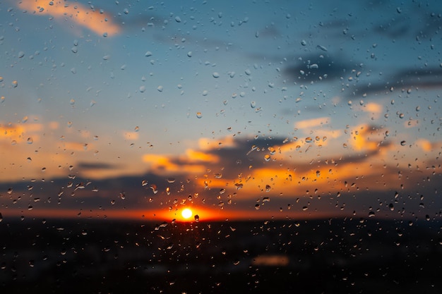 Closeup de gotas de chuva na janela no fundo do belo pôr do sol colorido fundo abstrato natural