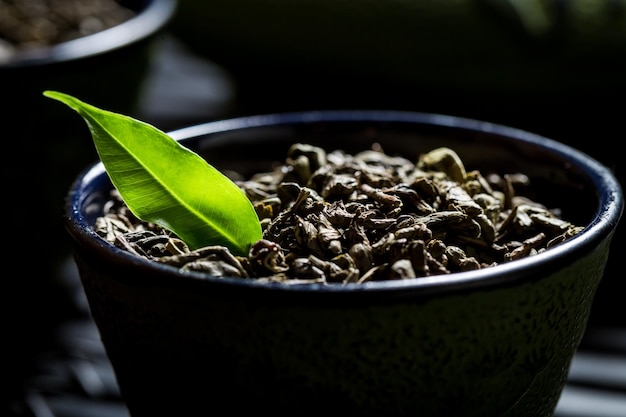 Closeup de grãos de chá verde na xícara de chá preta