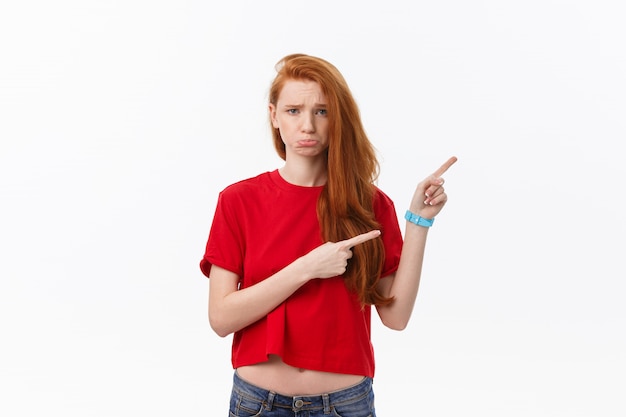 Closeup de grave estrita jovem usa camisa vermelha parece estressado e apontando para cima com o dedo isolado sobre o branco