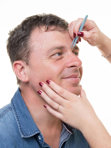 Closeup de homem com pinças, arrancando as sobrancelhas