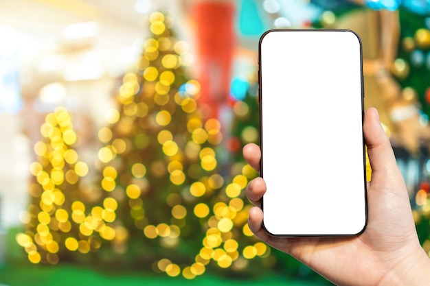 Closeup de imagens desfocadas de smartphones de uso feminino com bolas coloridas na decoração verde do fundo da árvore de natal durante o natal e o ano novo