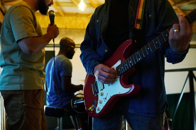 Closeup de jovem em jaqueta jeans e jeans azul tocando guitarra elétrica