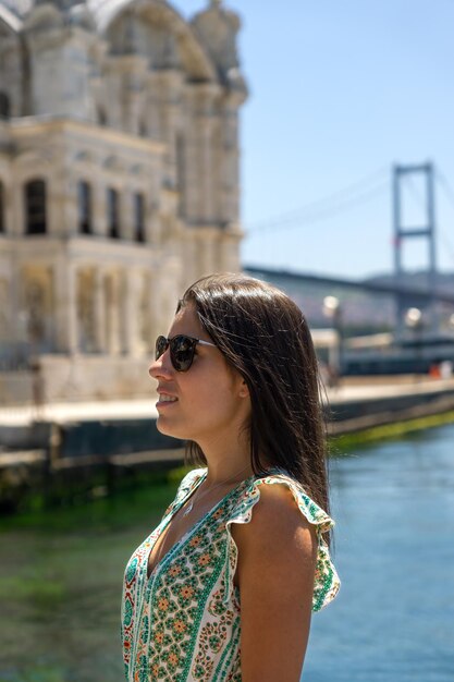 Closeup de jovem usando óculos e sorrindo ao lado da mesquita ortakoy em Istambul