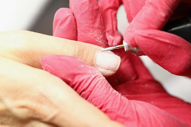 Foto closeup de manicure fazendo limpeza de unhas de especialista de cliente usando automático profissional