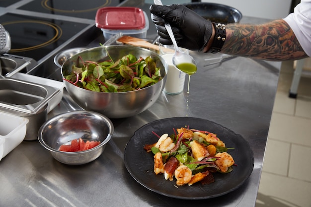 Closeup de mãos de chef preparando salada de camarão em uma cozinha de restaurante de luxo