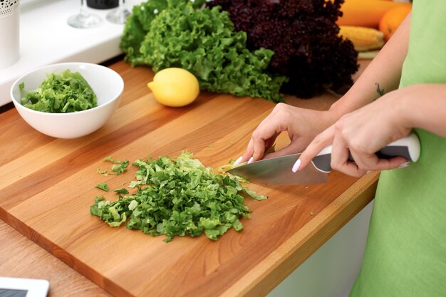 Closeup de mãos de mulher cozinhando salada de legumes na cozinha Refeição saudável e conceito vegetariano