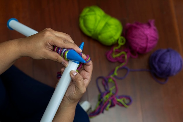 Closeup de mãos de mulher latino-americana39s segurando um tipo de agulhas plásticas retas de 25 mm com fios de material de lã de cores diferentes Conceito hobby atividade de lazer