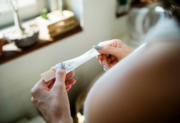 closeup de mãos de mulher segurando o teste de gravidez