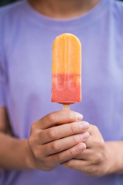 Closeup de mãos de mulher segurando um sorvete colorido. Sobremesa saborosa