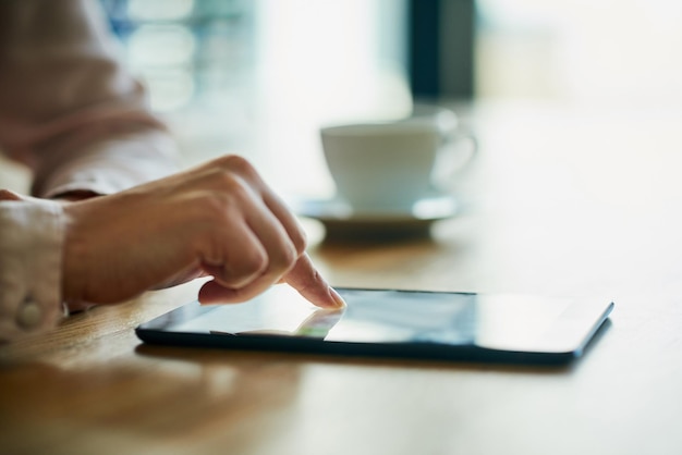 Closeup de mãos de negócios trabalhando em um tablet digital em um escritório moderno Profissional no trabalho na tela de toque navegando no mercado on-line para dados ou informações sobre investimento ou crescimento comercial