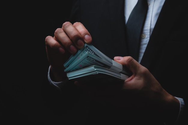 Closeup de mãos de um jovem empresário e empresário vestindo roupas formais de terno e gravata, segurando e contando papel-moeda
