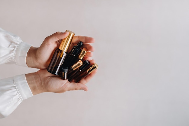 Closeup de mãos femininas segurando muitas garrafas de óleo essencial de aromaterapia