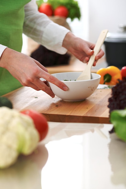 Closeup de mãos humanas cozinhar salada de legumes na cozinha na mesa de vidro com reflexão. Refeição saudável e conceito vegetariano