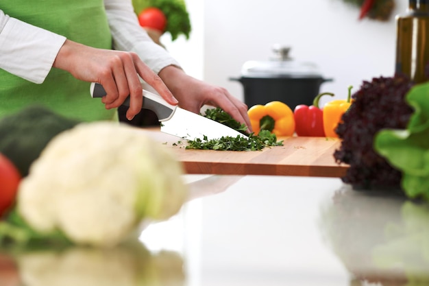 Closeup de mãos humanas cozinhar salada de legumes na cozinha na mesa de vidro com reflexão. Refeição saudável e conceito vegetariano