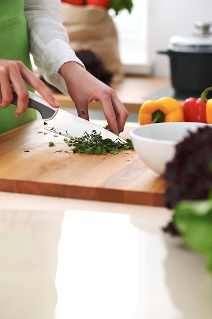 Closeup de mãos humanas cozinhar salada de legumes na cozinha na mesa de vidro com reflexão. Refeição saudável e conceito vegetariano