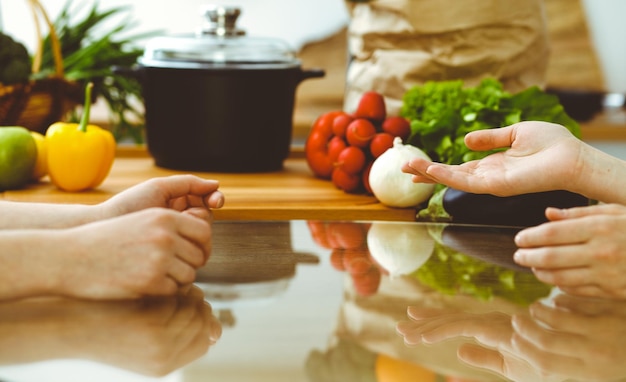 Closeup de mãos humanas discutindo algo enquanto cozinha na cozinha Mulheres falando sobre menu Jantar em família, amizade e conceito de estilo de vida