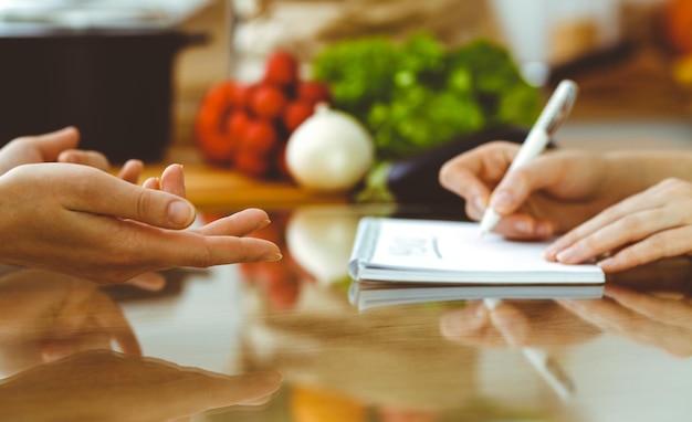 Closeup de mãos humanas discutindo algo enquanto cozinha na cozinha Mulheres falando sobre menu Jantar em família, amizade e conceito de estilo de vida