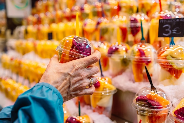 Closeup de mãos leva potes de salada de frutas preparadas para levar salada de frutas frescas kiwi manga morango