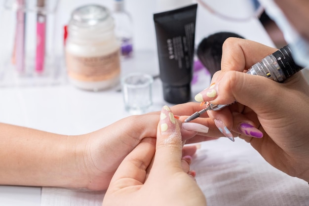 Closeup de mãos lixando as unhas de uma mulher com uma lixa de unha Serviço de manicure profissional