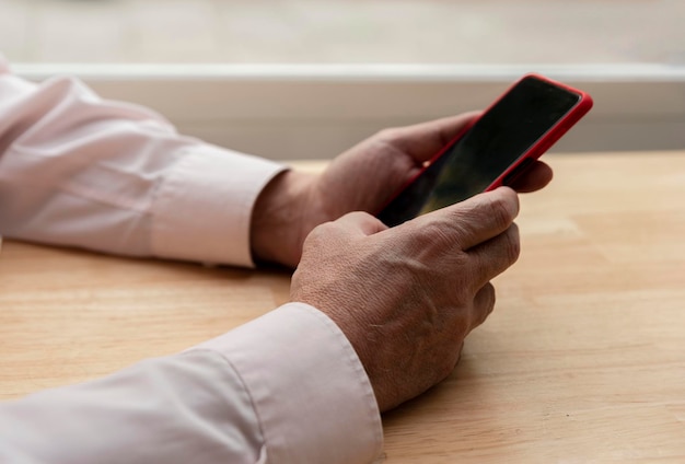 Closeup de mãos masculinas mais velhas digitando uma mensagem em um telefone celular