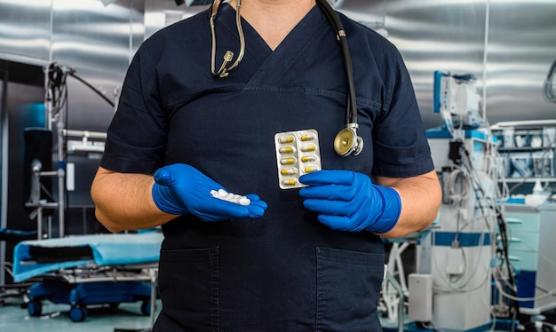 Closeup de médico em uniforme azul escuro segurando um comprimido com estetoscópio